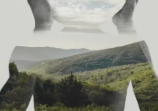 A human silhouette filled with an open landscape, mountains and sky within